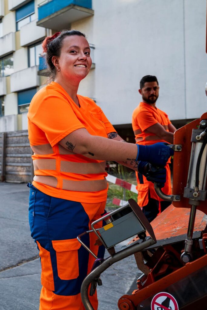Soraya Sägesser fährt auf dem Trittbrett des Müllwagens.